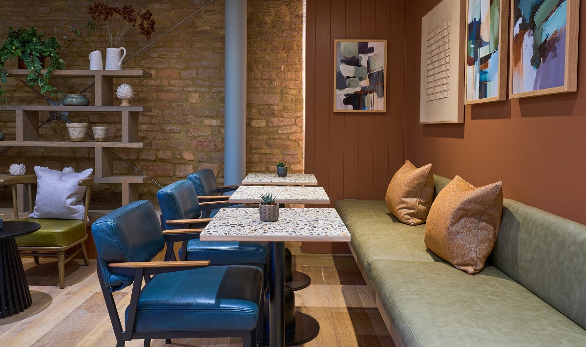 green banquette opposite blue chairs and exposed brick wall in The Grain Store