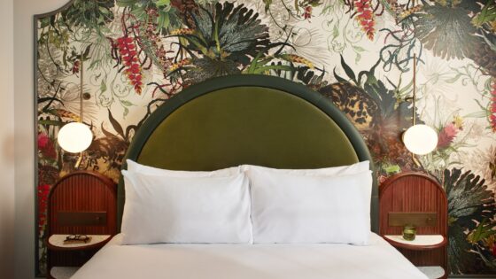 floral wallpaper behind moss green bedhead in Hype London guestroom