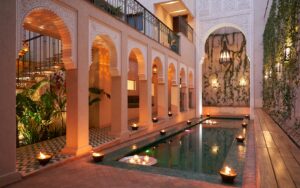 candlelight and arches around courtyard pool in IZZA Marrakech