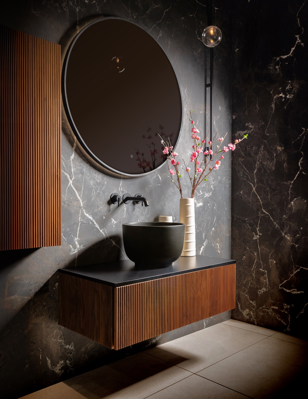 round bathroom mirror above wooden wall hung vanity with dark bowl shaped basin in japanese inspired bathroom