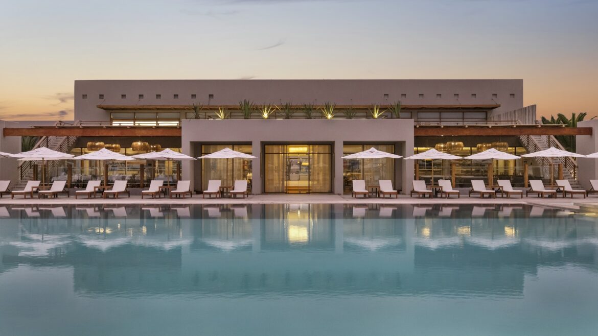 view across swimming pool to parasols and resort building at dusk