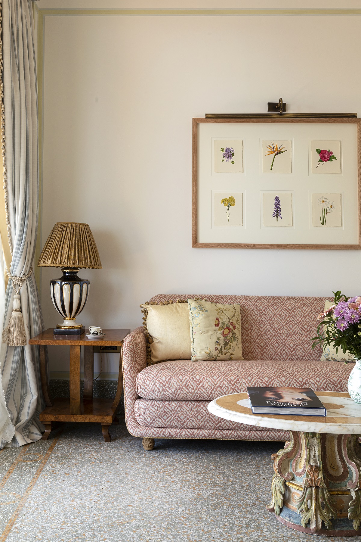 pink couch with botanical print artwork on wall above