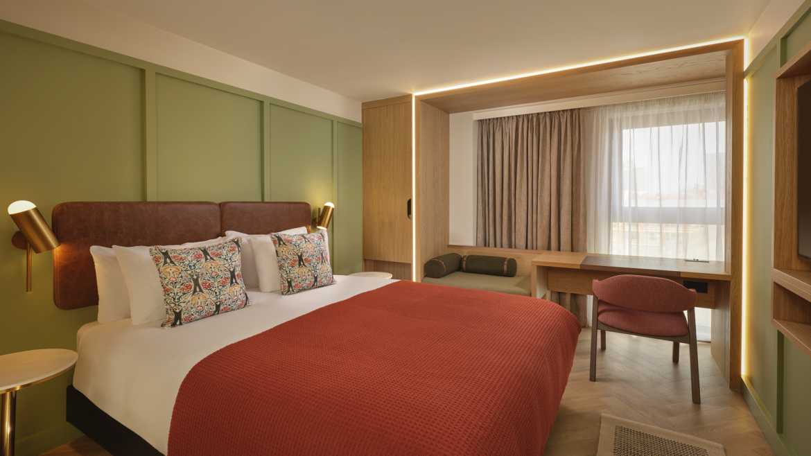 green wall and orange throw on bed in guestroom at The Reach Manchester