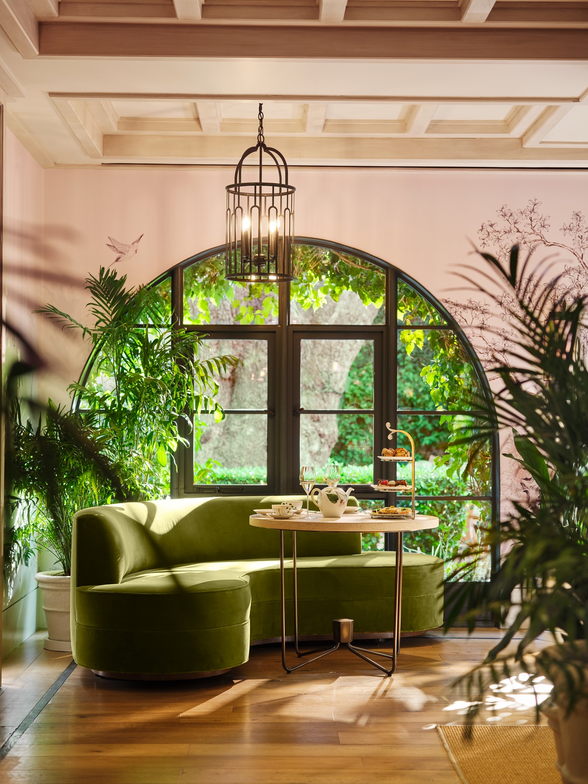 curved green couch in front of garden window and plants