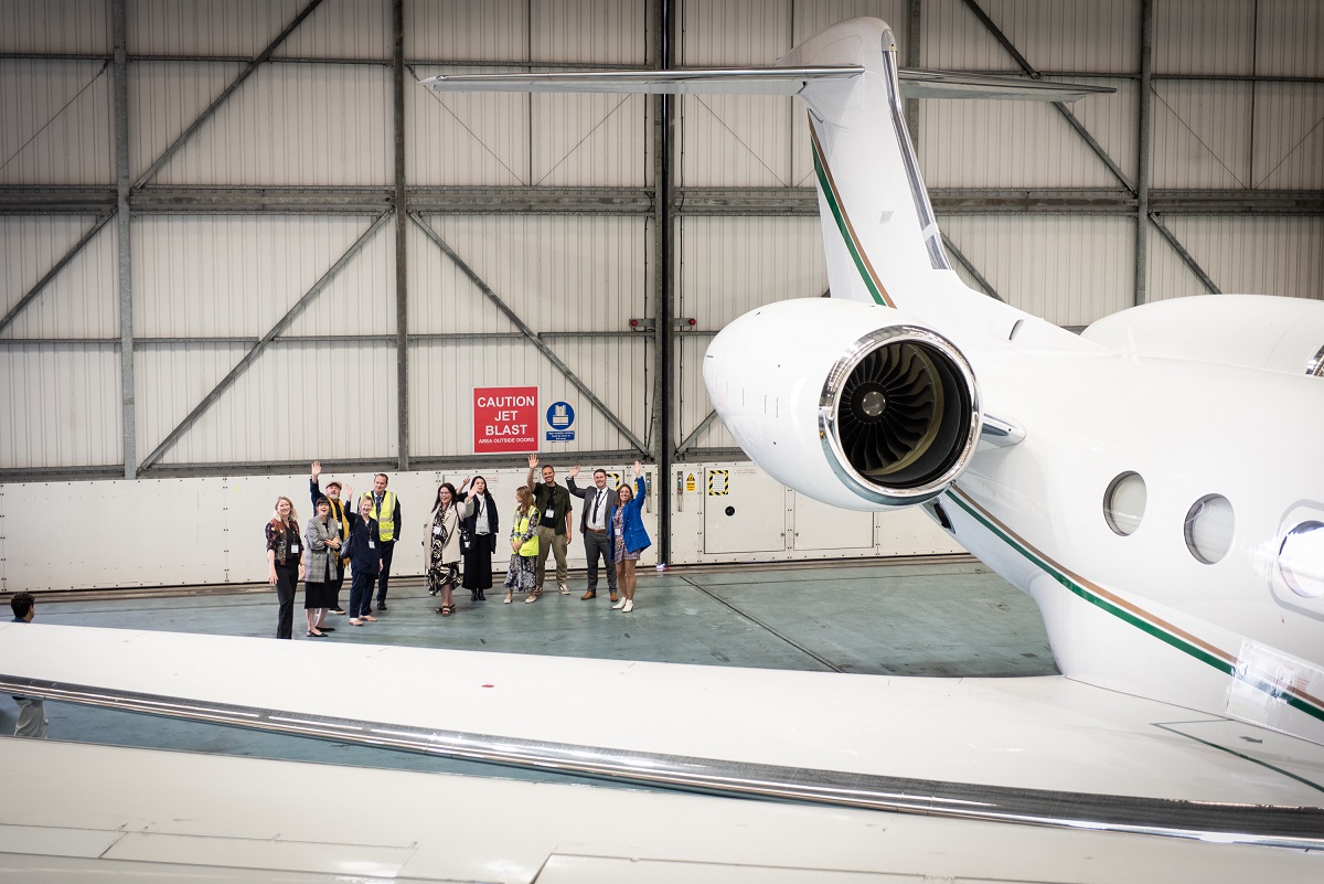 The attendees all wave beside a private jet