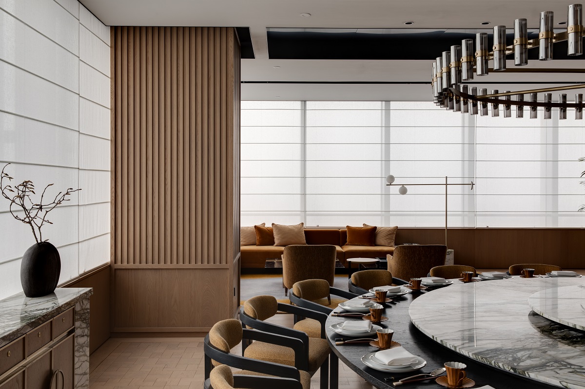 A private dining space with a neutral colour palette is juxtaposed by dark metals, black and white marble surfaces and blackened wooden details.