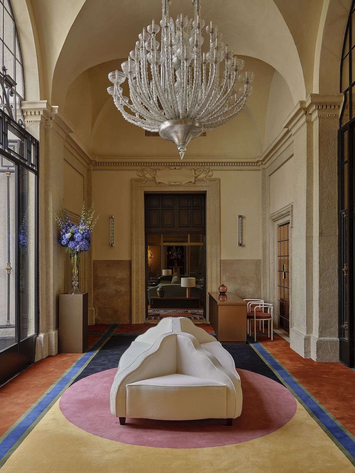 hotel reception with central white seating under glass chandelier and on a geometric bespoke carpet