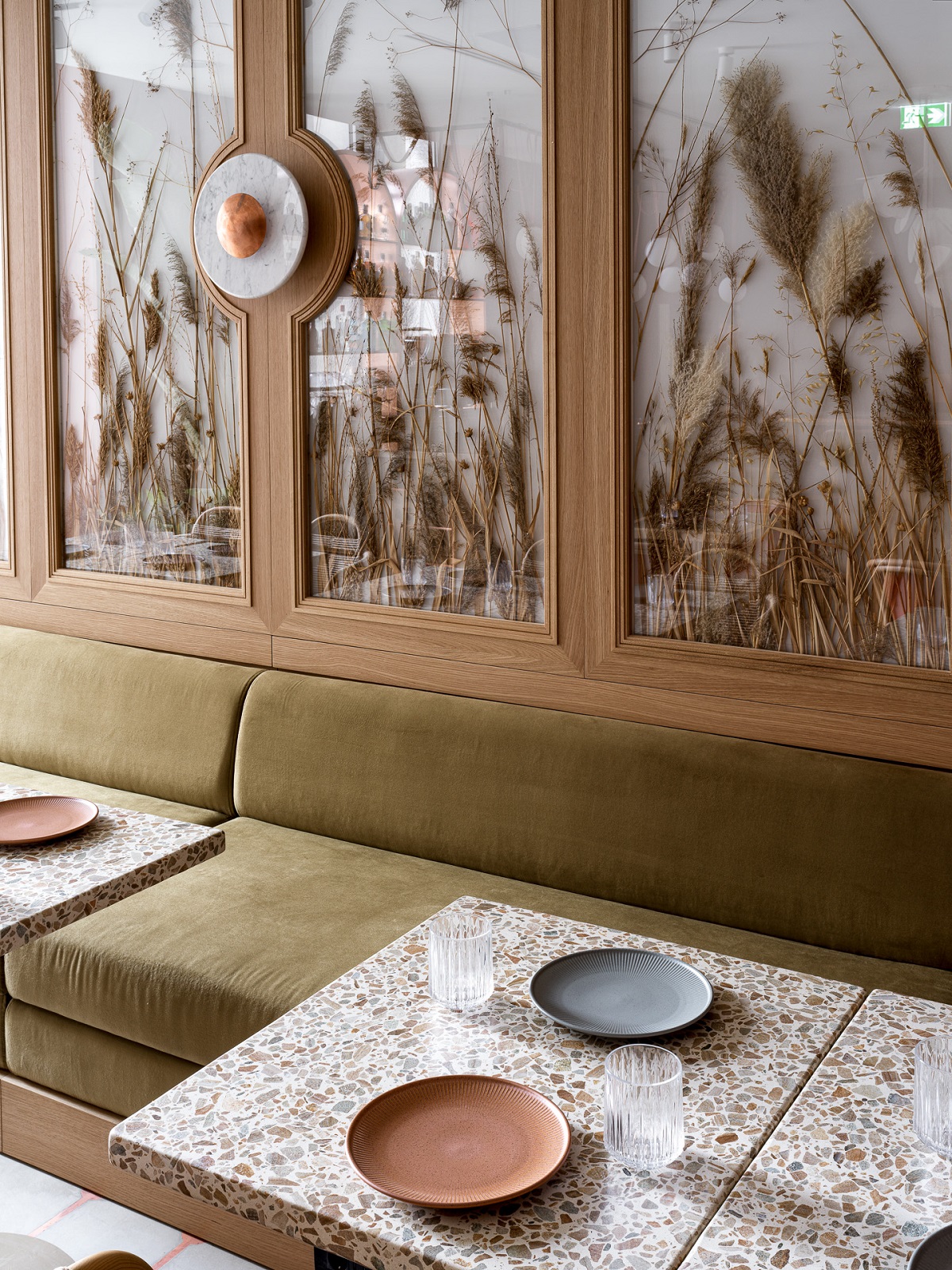 table in front of glass wall panel with dried grasses