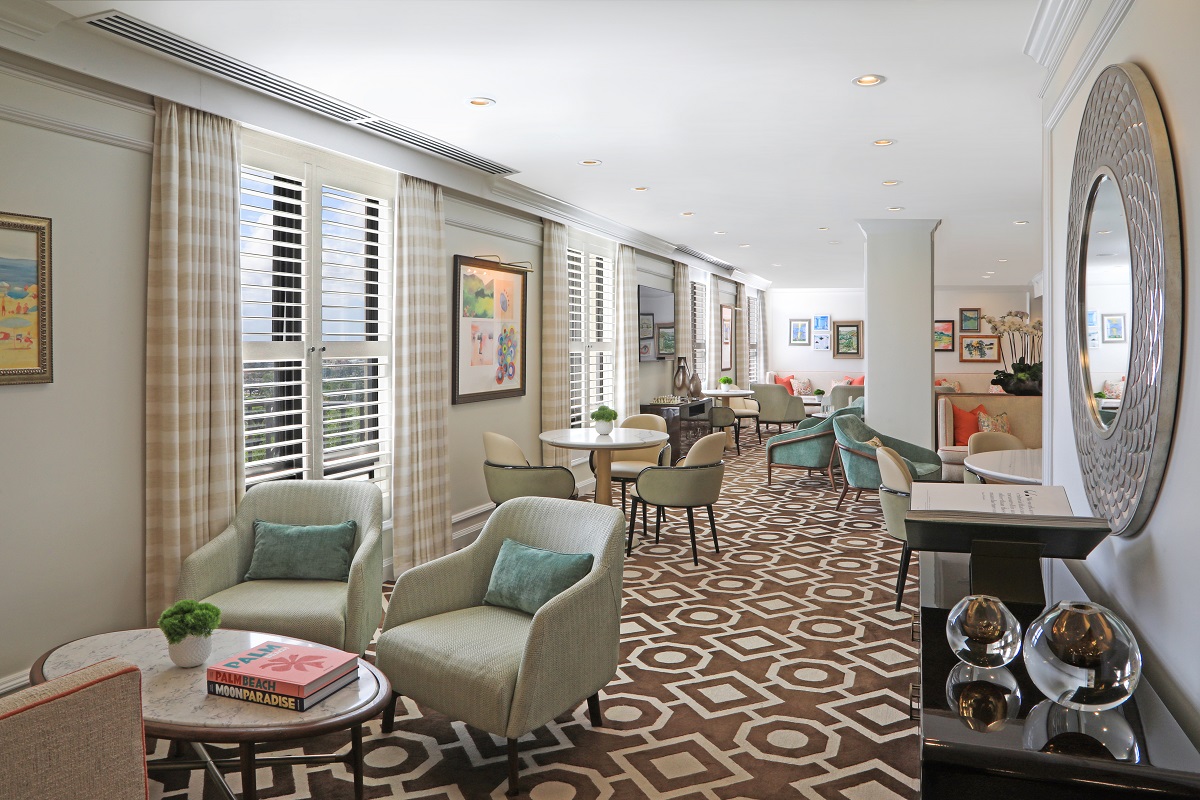 brown and cream patterned carpet in hotel hallway with seating and art deco elements