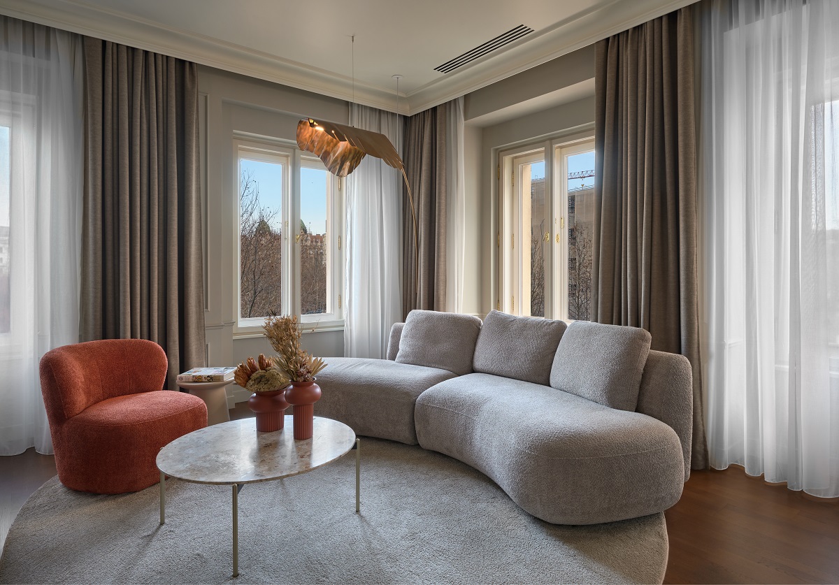 curved couch on circular carpet in window corner of guestroom