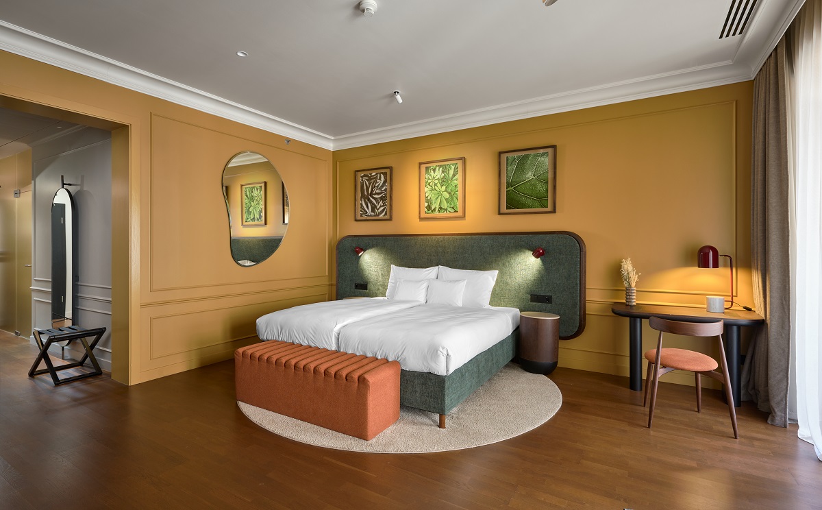 Guest rooms in green and light terracotta tones with wooden floors