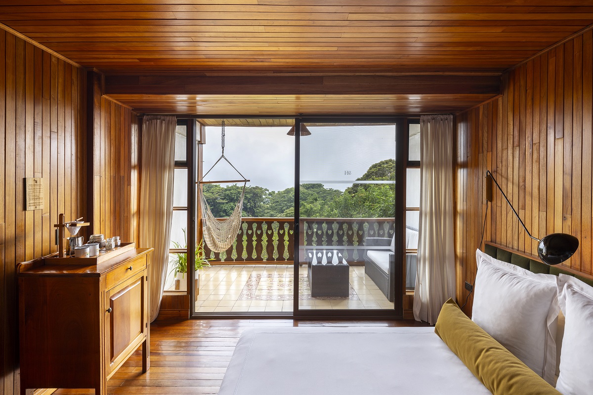 view from hotel belmar bed onto deck with hanging chair and view across treetops