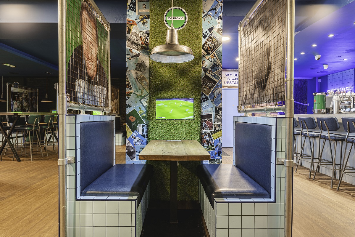 seating booth with sport images and astro turf in sky blue tavern