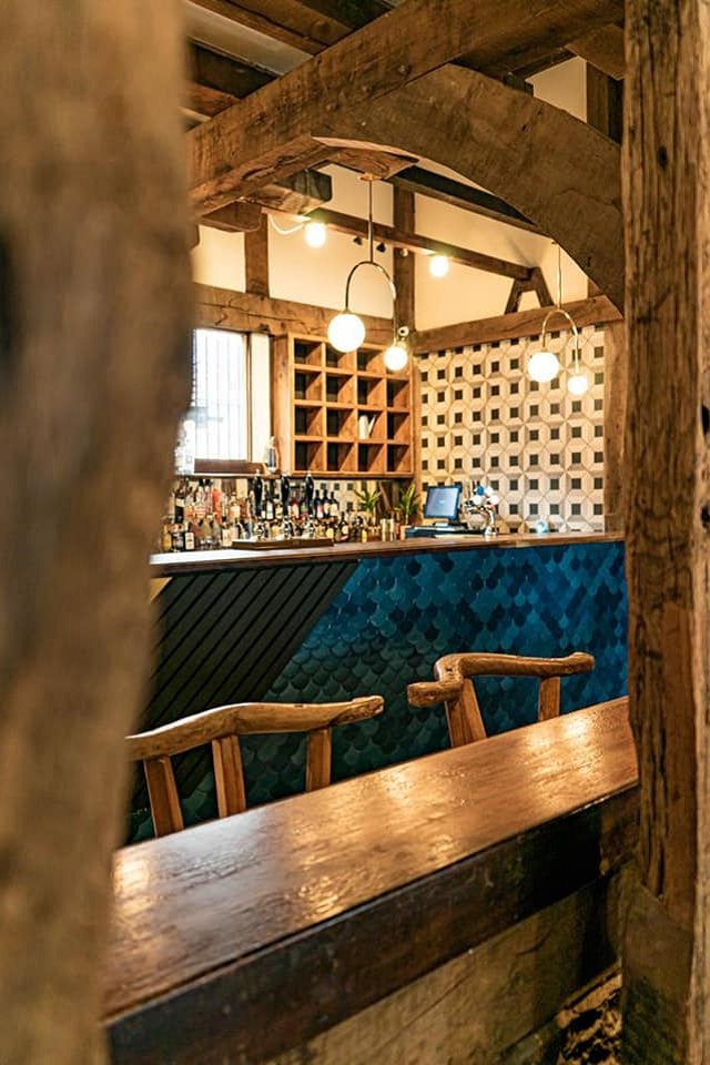 view through old wooden beams to blue tiled bar