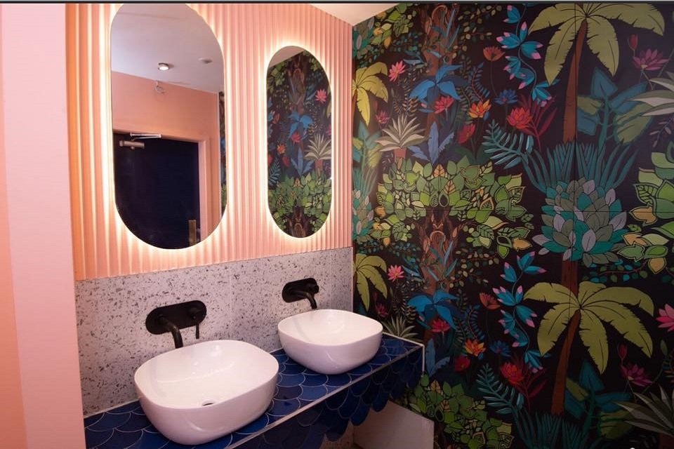 pink powder room with dark blue and green wallpaper contrast