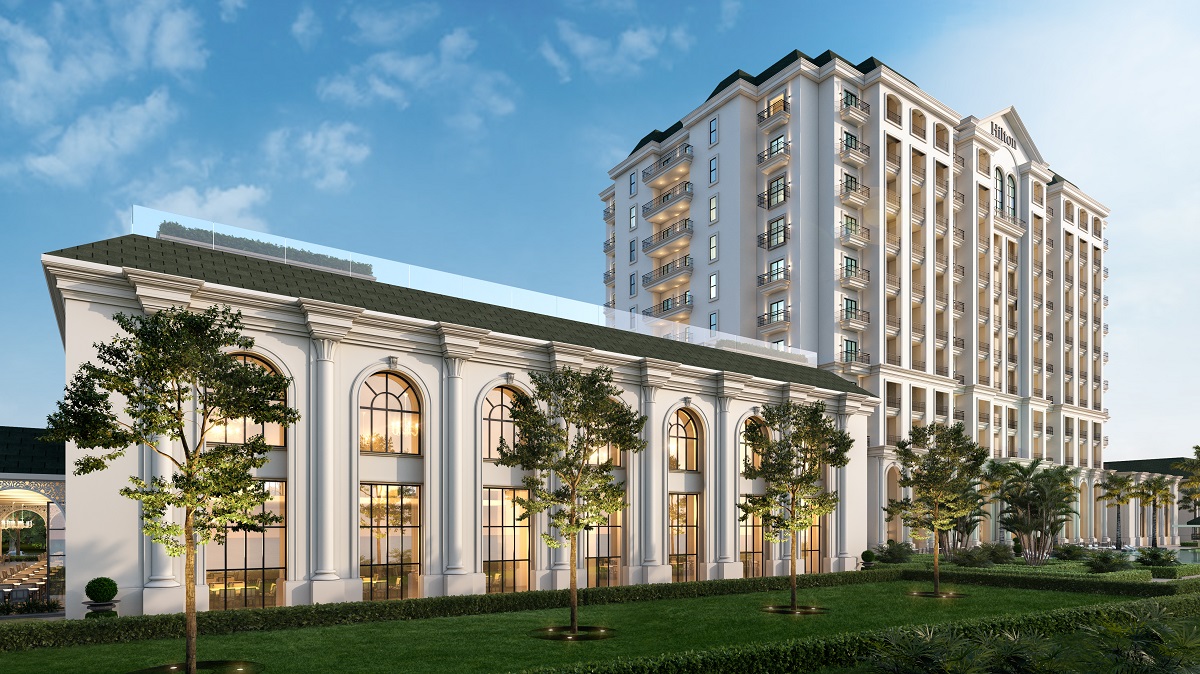 The exterior of Hilton Georgetown shows a grand white building with elevated and lower levels and high arching floor-to-ceiling windows 