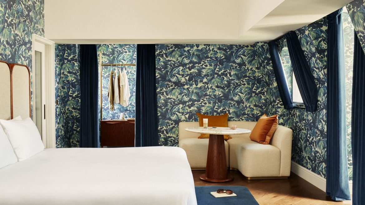 A grand suite with patterned blue walls, high ceilings, and superking bed