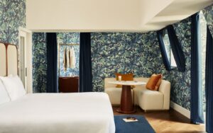 A grand suite with patterned blue walls, high ceilings, and superking bed