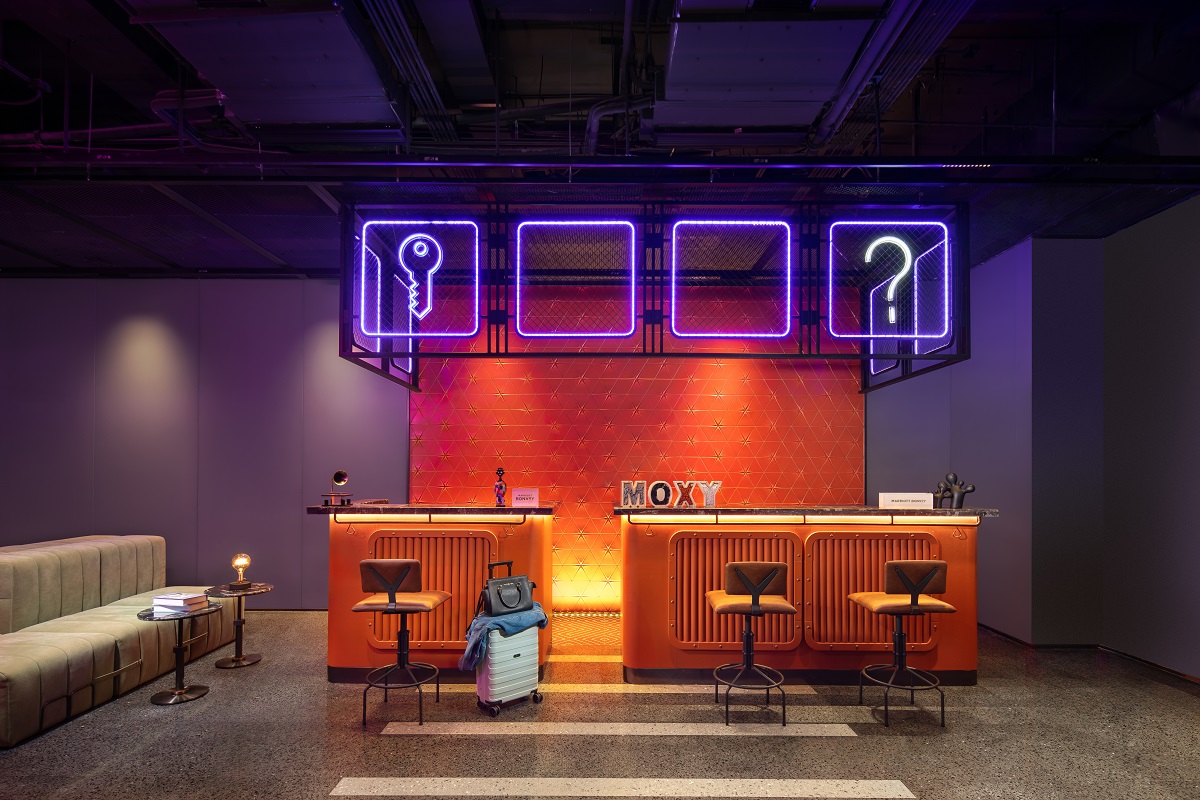 moxy reception with neon signage and retro orange tiled surfaces