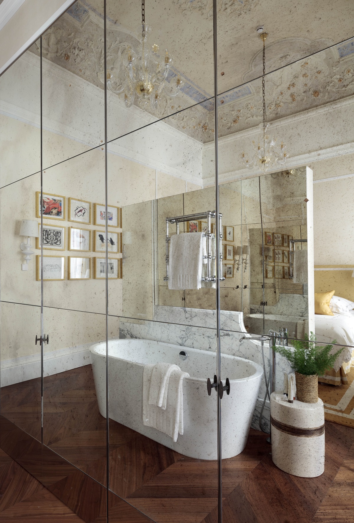 freestanding bath and Italian moulded ceiling reflected in mirrored wardrobe door panels