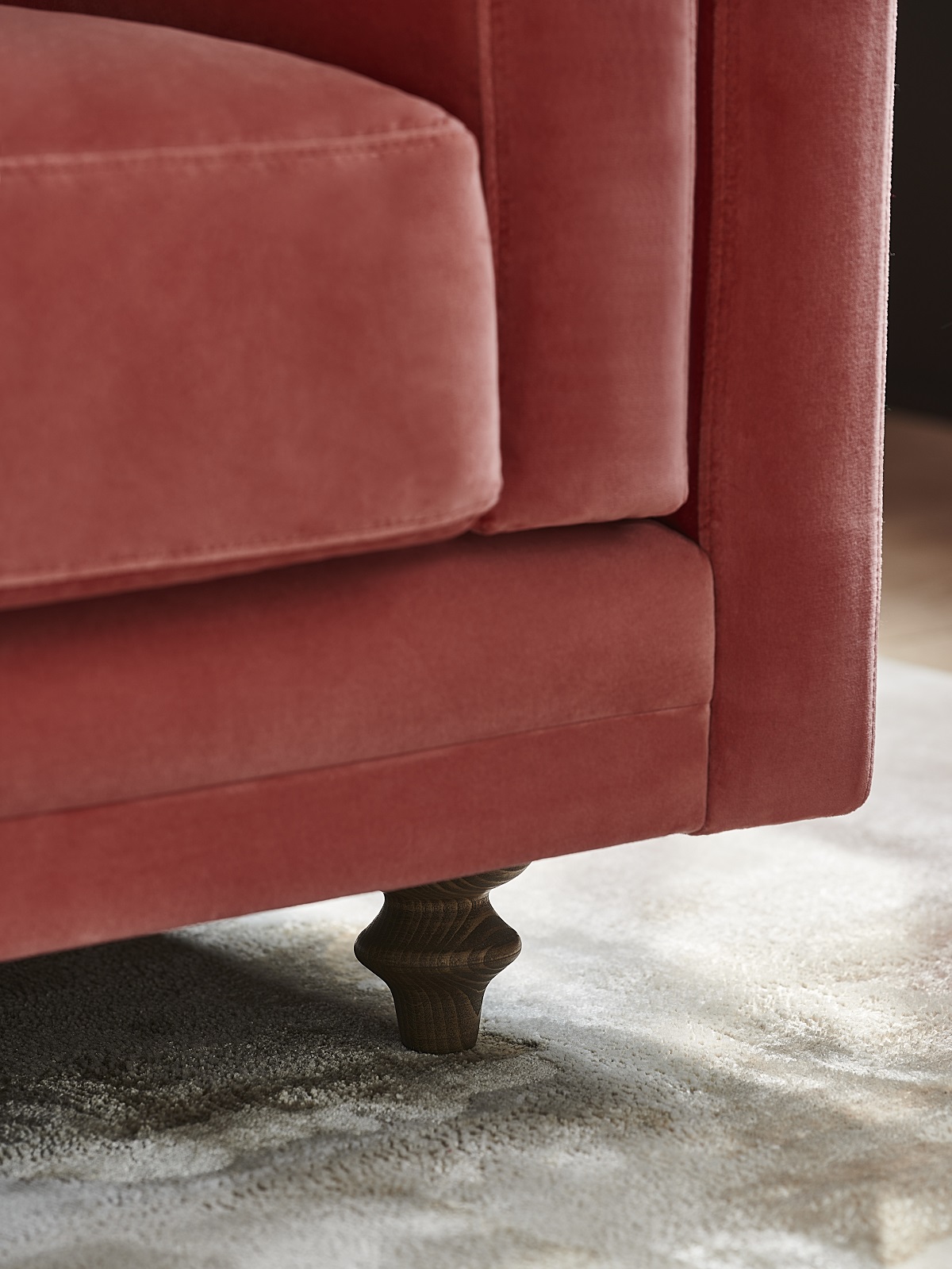 close up corner detail of pink upholstered sofa 