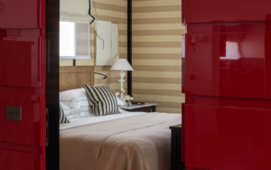 view through red doors into bedroom with striped walls in Rocco Forte House Milan