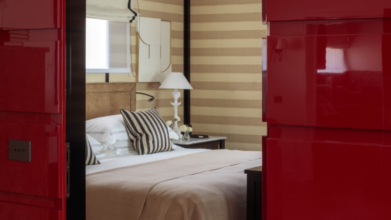 view through red doors into bedroom with striped walls in Rocco Forte House Milan