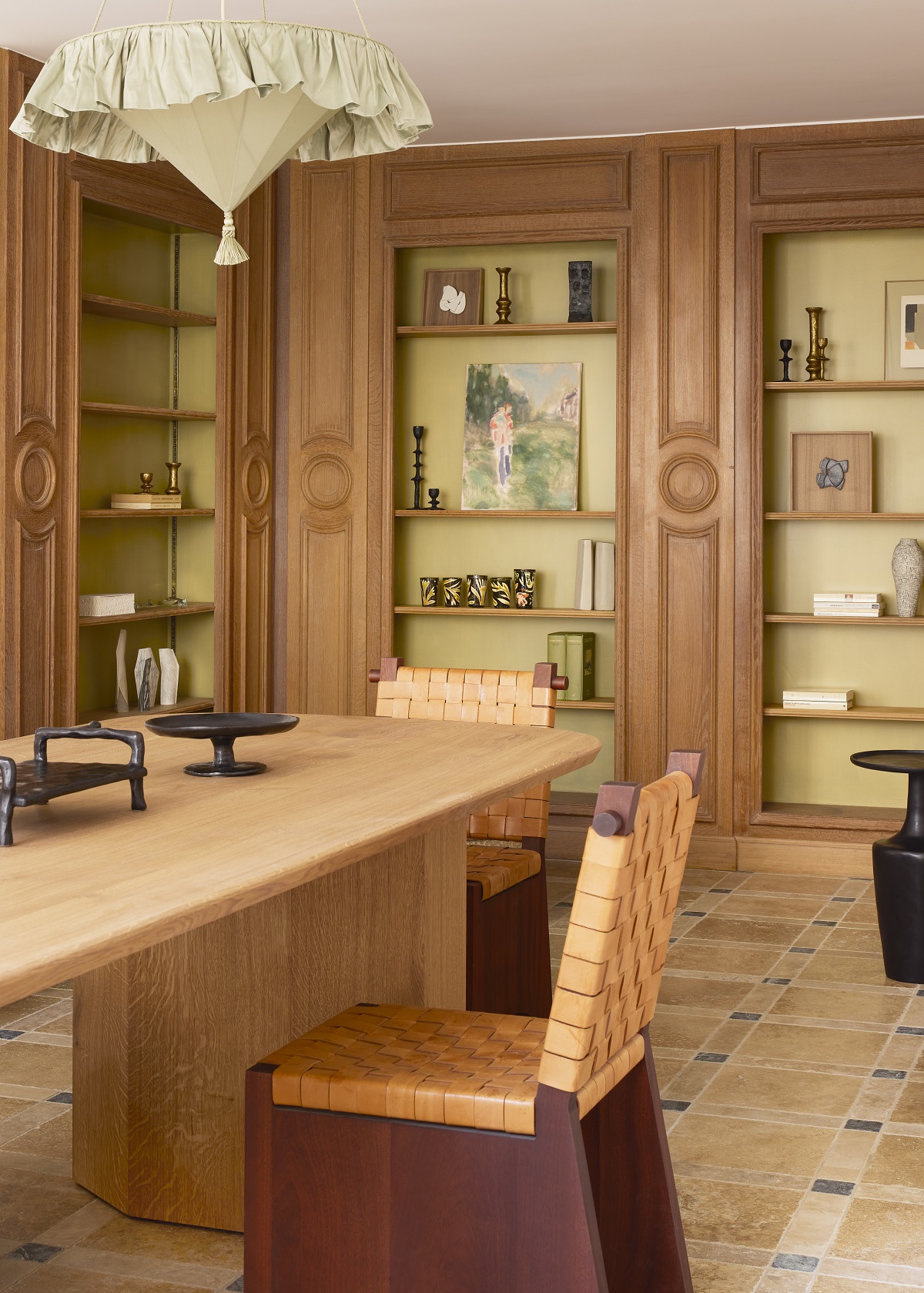 wood and leather chair at wooden dining table with shelving and art in background