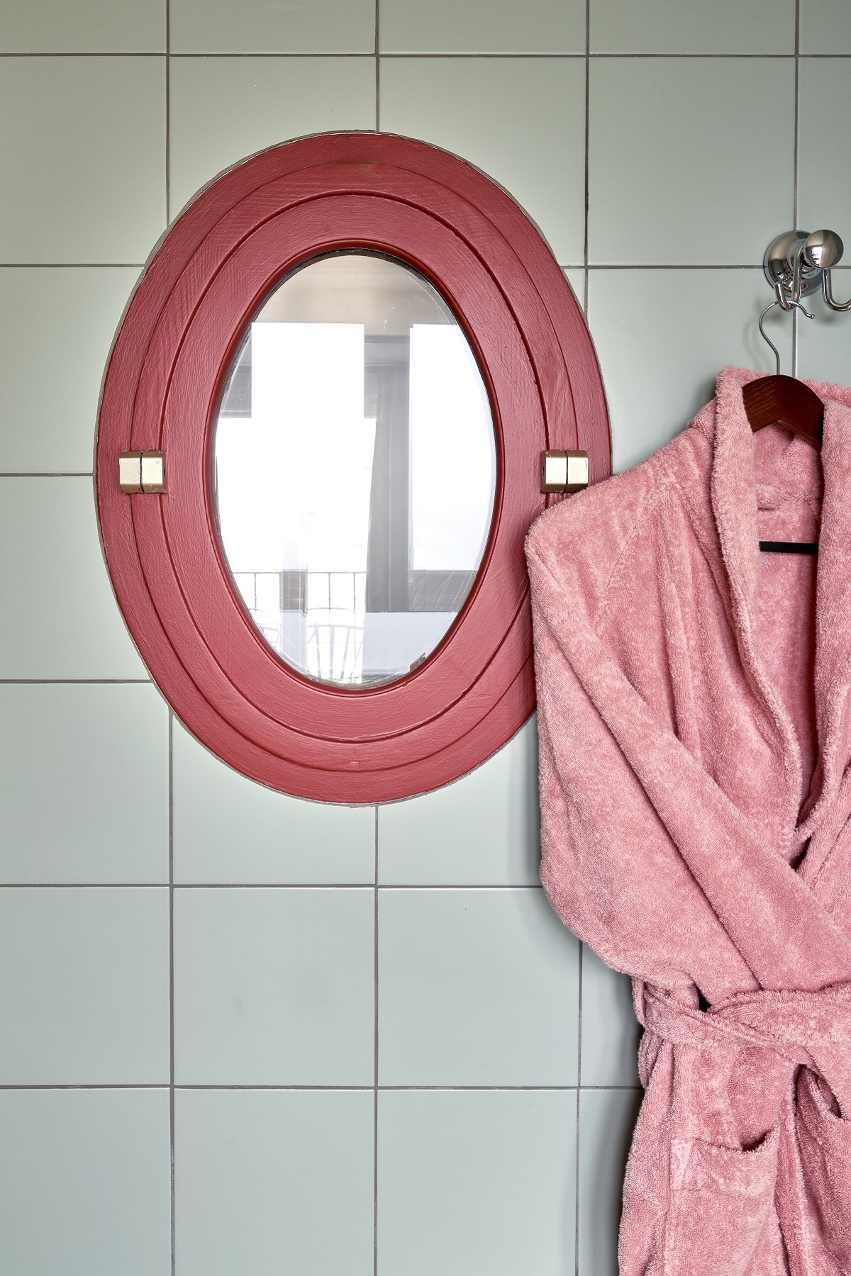 retro pink bathrobe hanging next to pink framed mirror