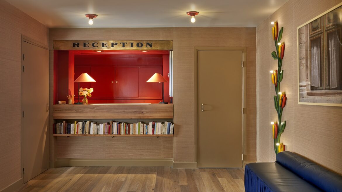 Hotel de la Boetie reception desk with orange background and blue couch in the foreground