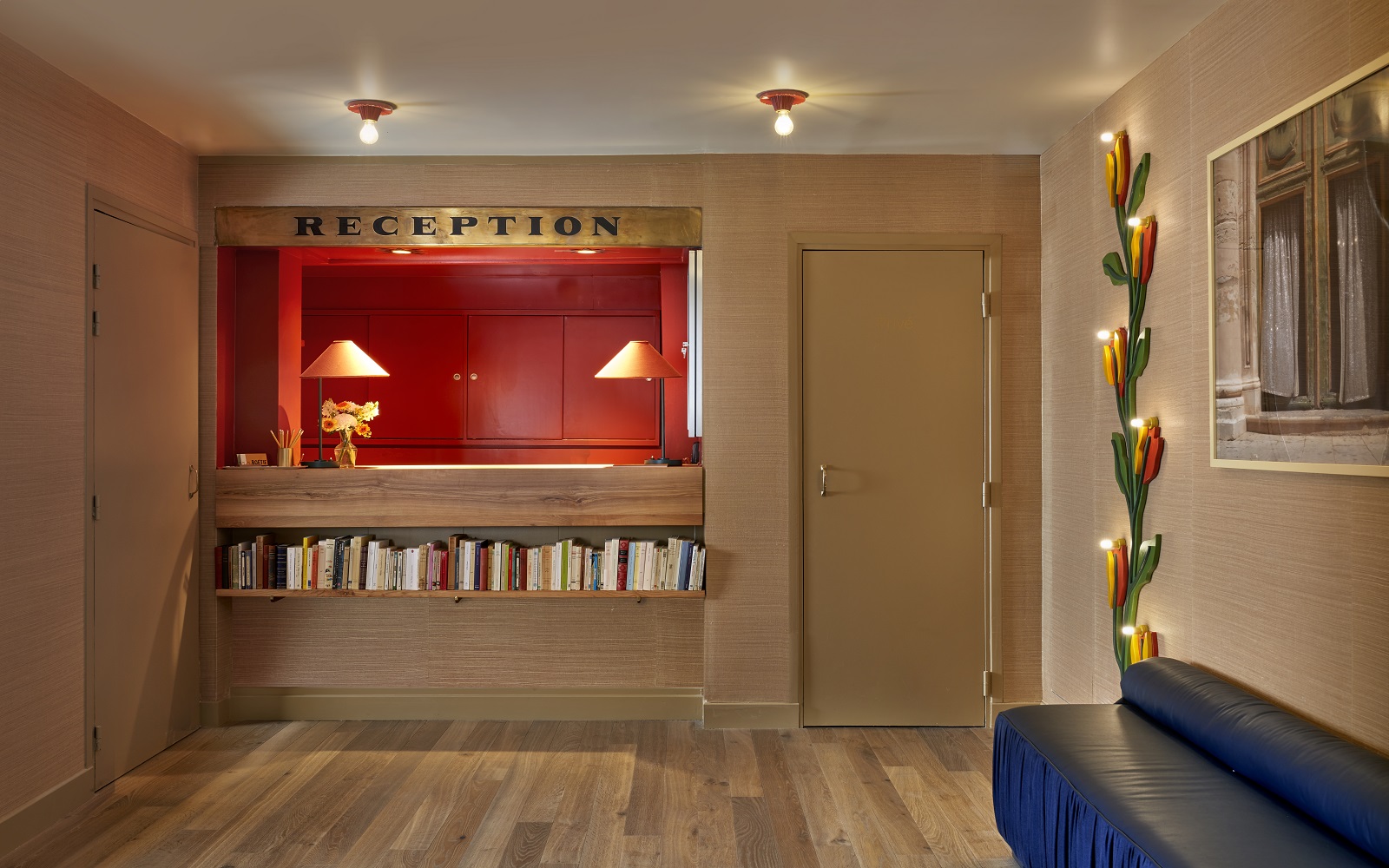 Hotel de la Boetie reception desk with orange background and blue couch in the foreground