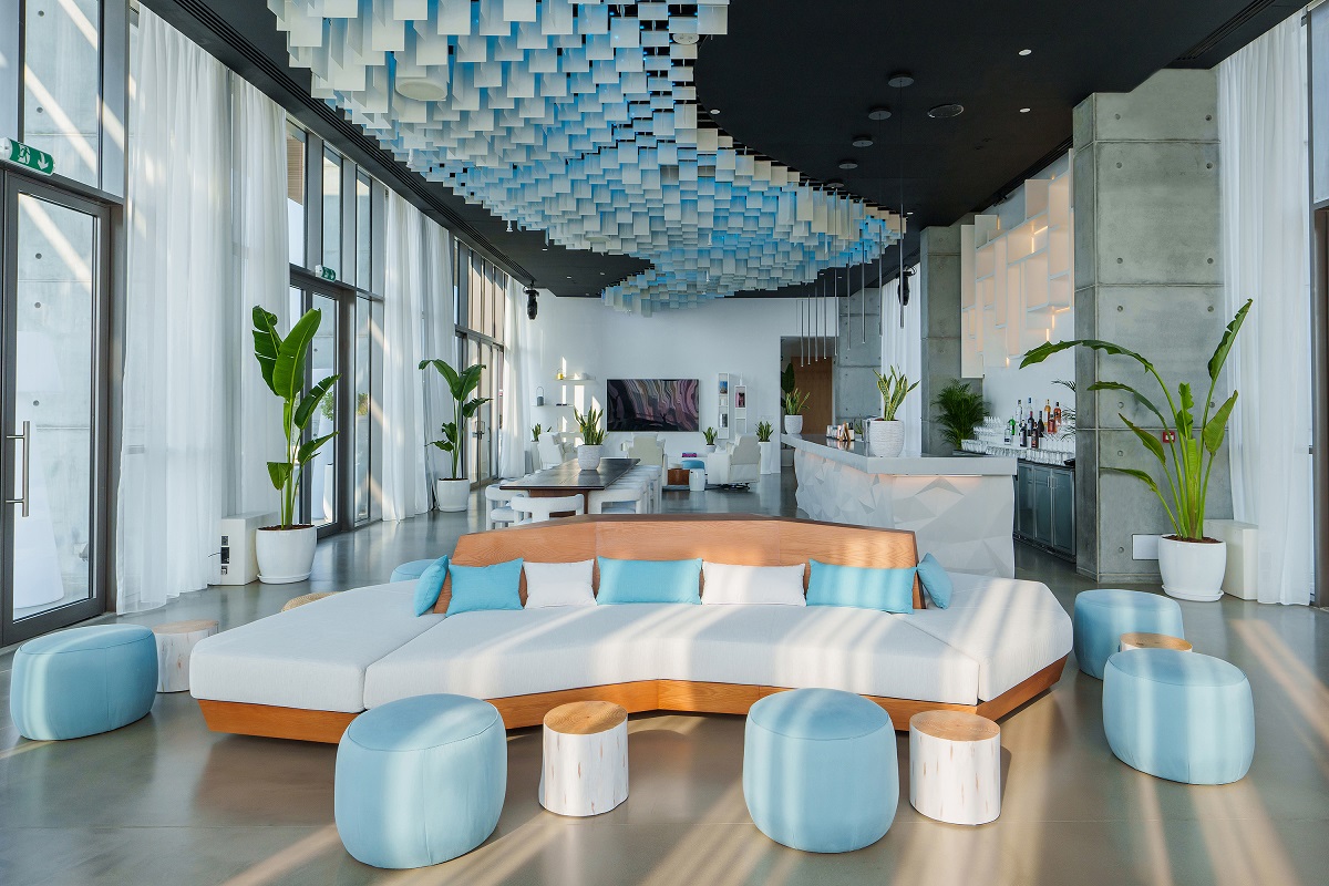 turquoise and white living room space with curved couch in Nikki Beach Dubai