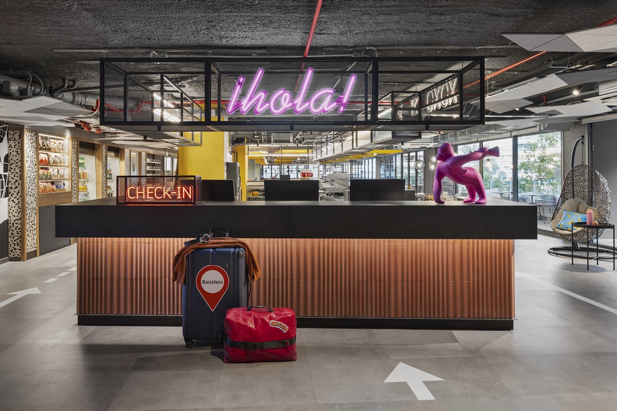 suitcase in front of reception with neon sign in Moxy Barcelona