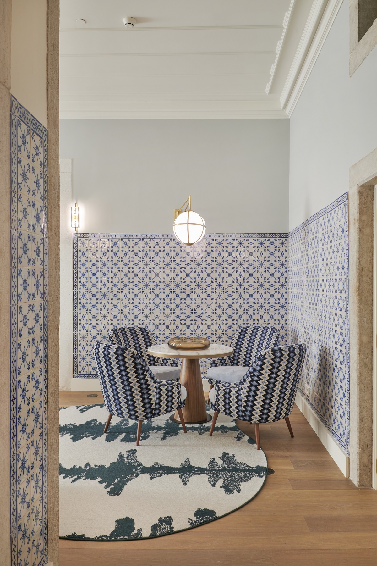 blue wall tiles behind blue striped chairs with round blue and white carpet