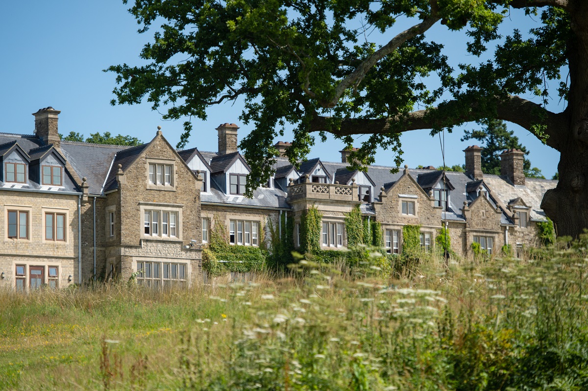 The exterior view of South Lodge showing a historic building nestled between verdant landscape