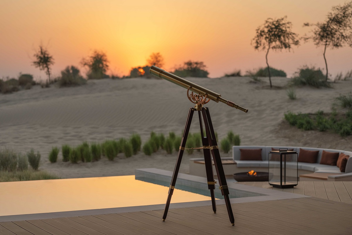 telescope looking out over villa pool and sunset across the desert