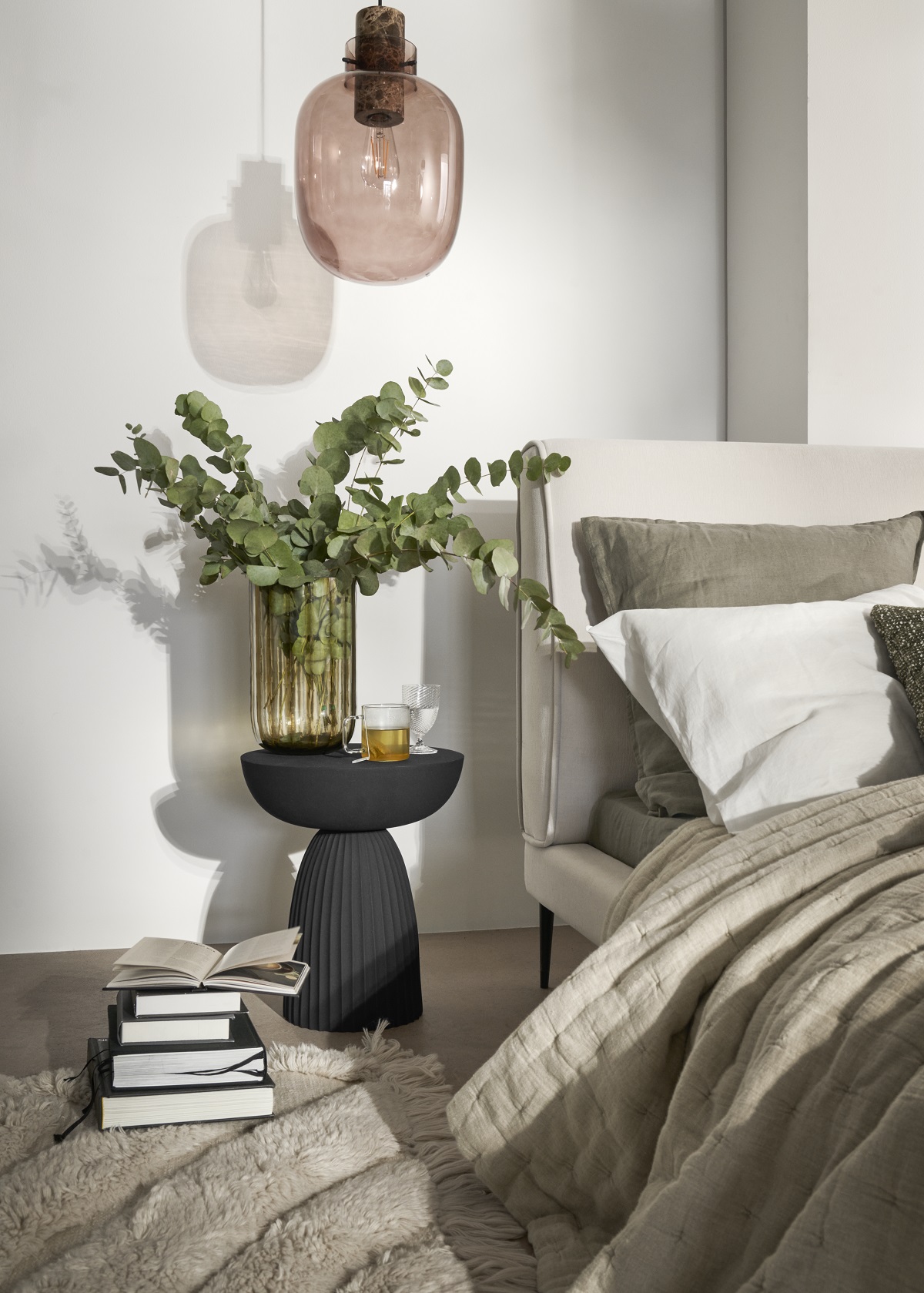 overhead bedside glass pendant light above table with plant and books