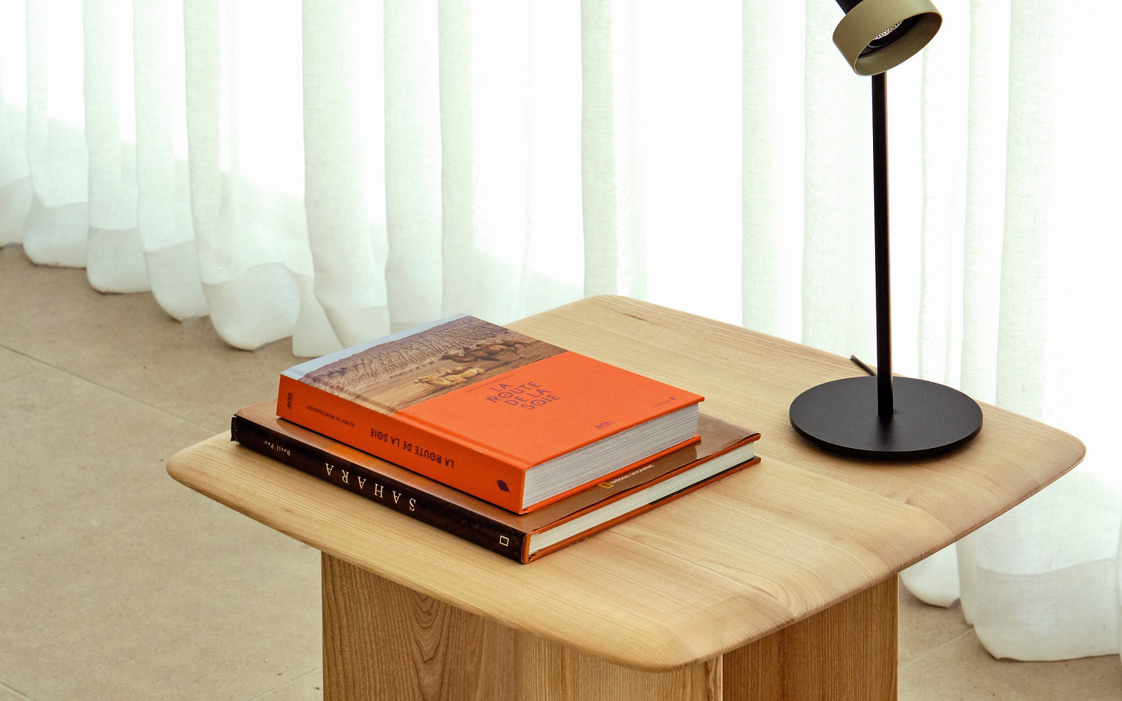 wooden side table from Ligne Roset Contract with lamp and books