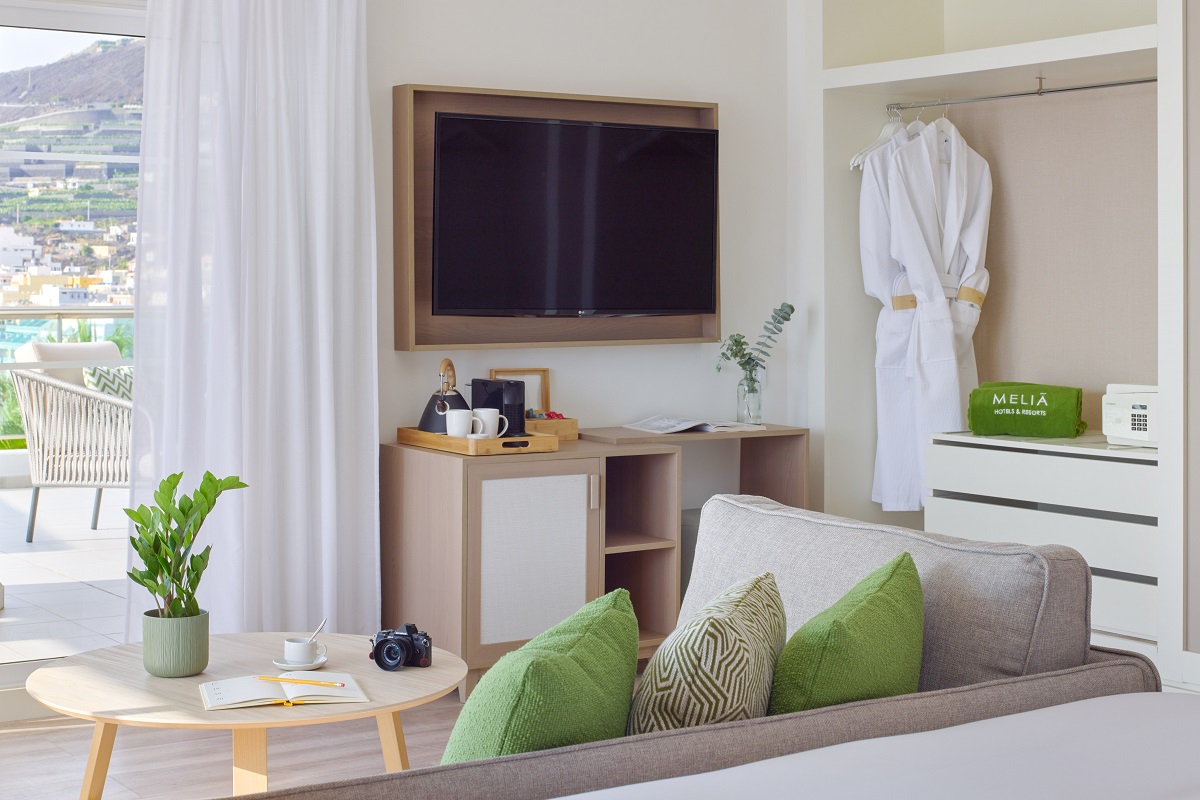 white and cream hotel guestroom with green cushions and accents