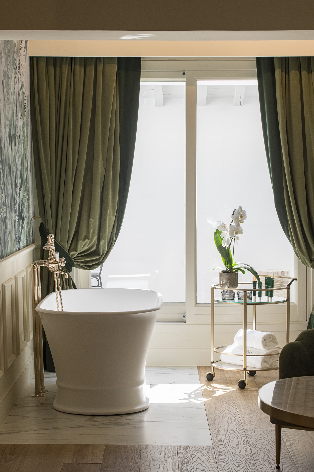 freestanding bath and green velvet drapes in hotel bathroom