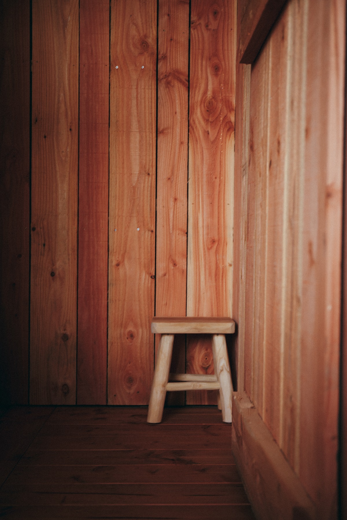 wooden stool against wooden panelled wall