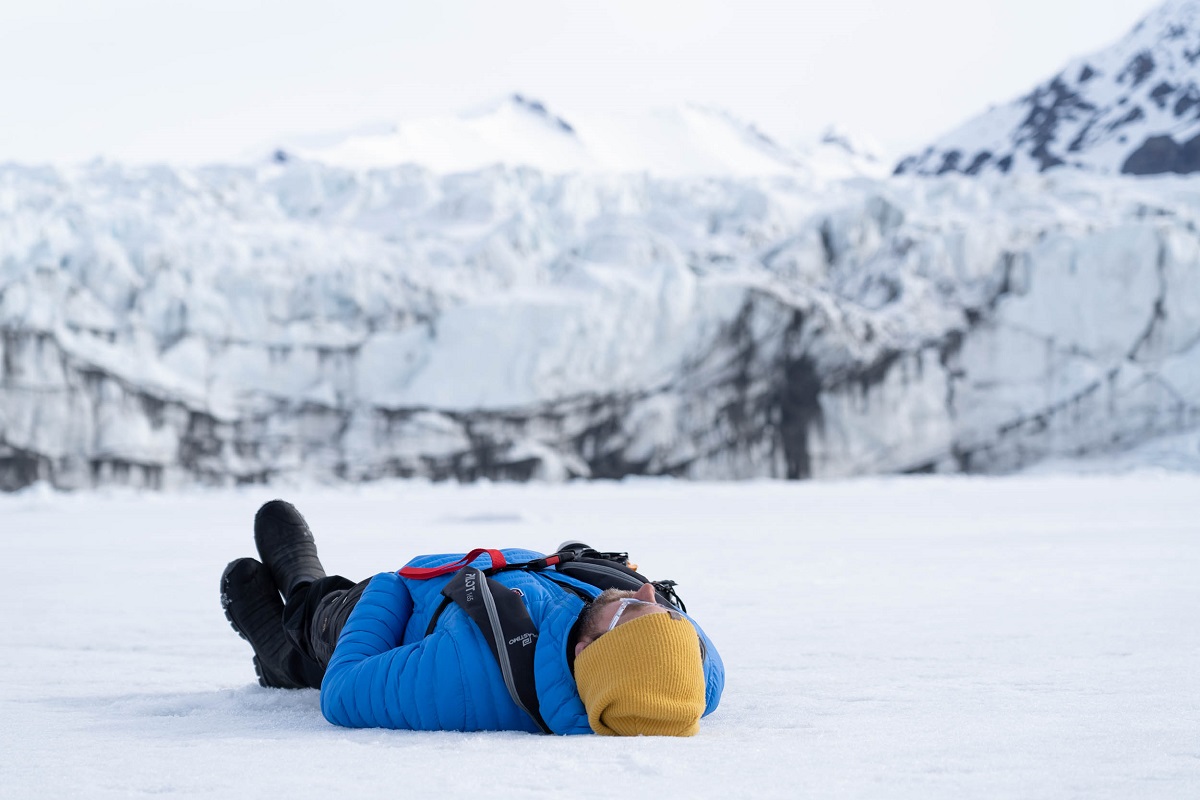 man lying down on snow in arctic