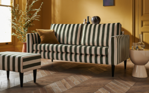 Lounge area with green stripe sofa and footstool with mustard walls, from sofa.com