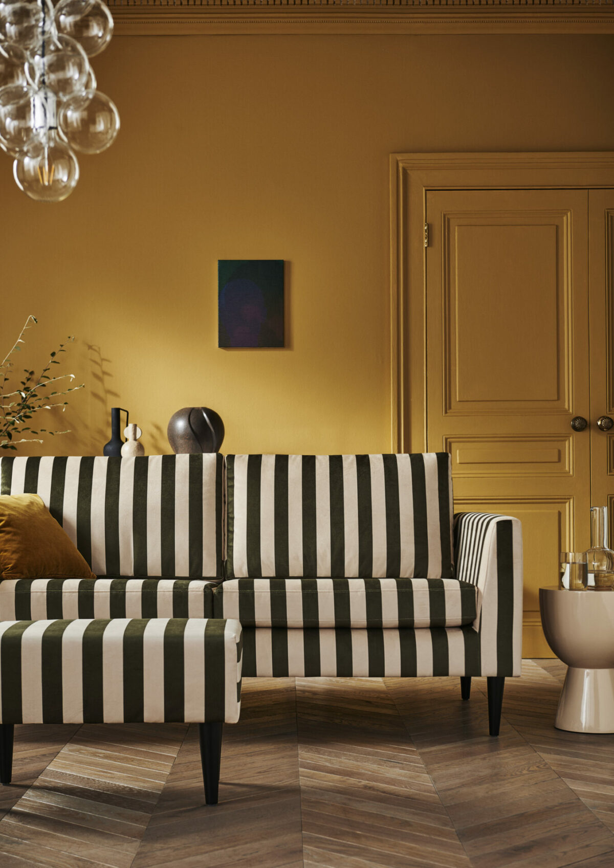 Jack-3-Seater-Sofa-and-Round-Footstool-in-Green-Stripe in mustard coloured room.