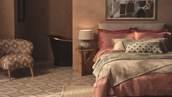 bedroom with layered textiles on bed and patterned tiles from Hyperion on the floor