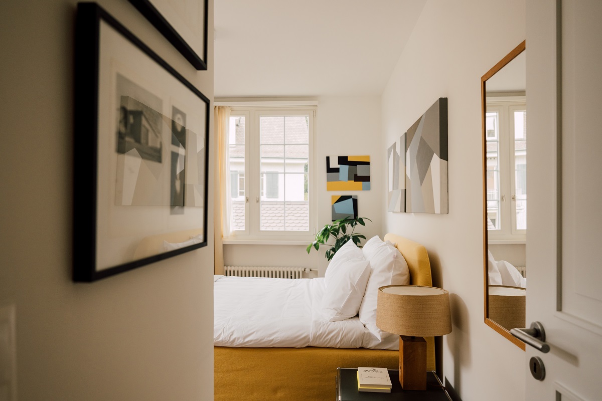 view into guestroom with art on the wall and white bed linen