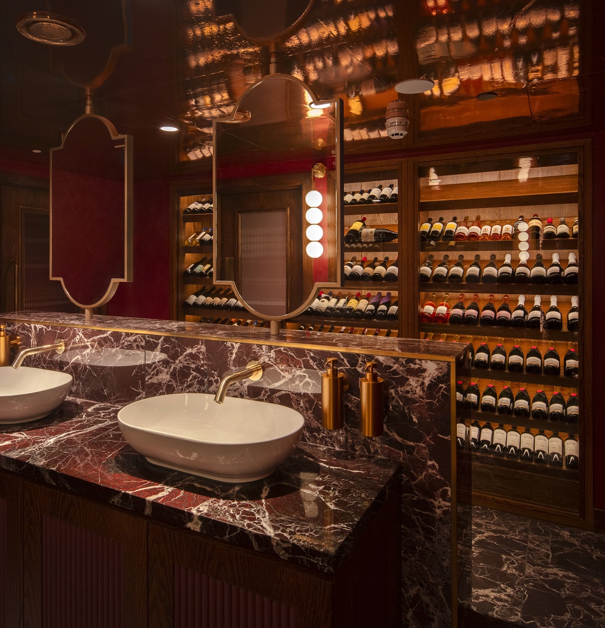 marble vanity in restaurant bathroom with backlit wall into the wine cellar