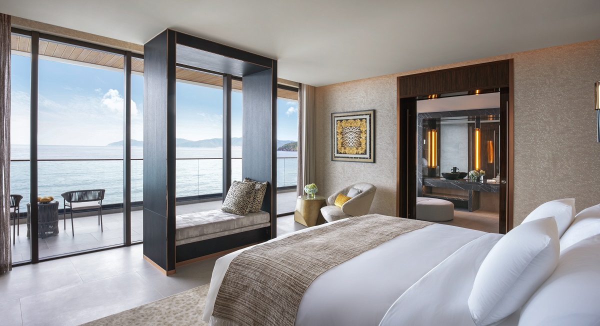 bed with white linen facing framed ocean view in Feroce Villa at Le Corail