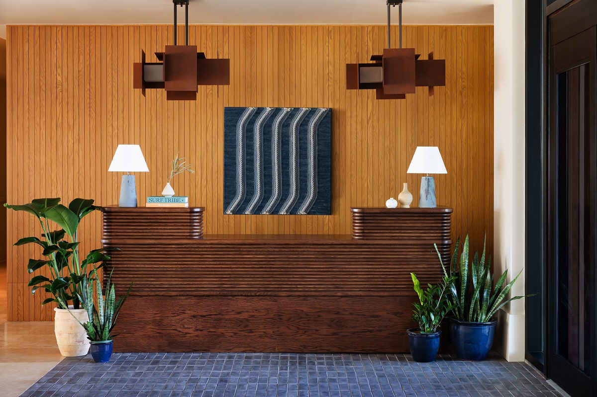  wood-accented entryway with a minimal wood and stone-clad desk in Trailborn Surf & Sound lobby