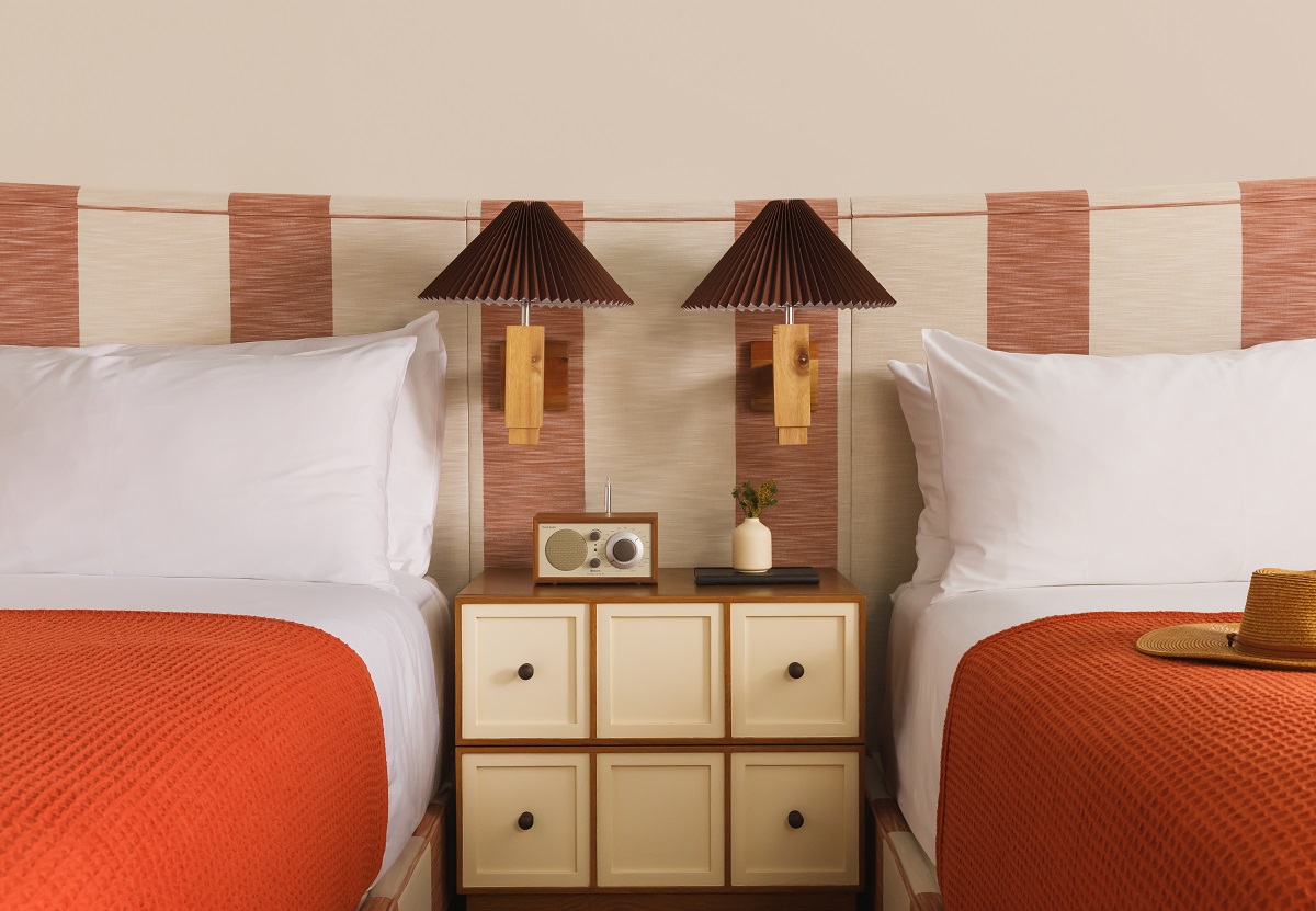 orange bedcover, white linen and 2 wooden bedside lights